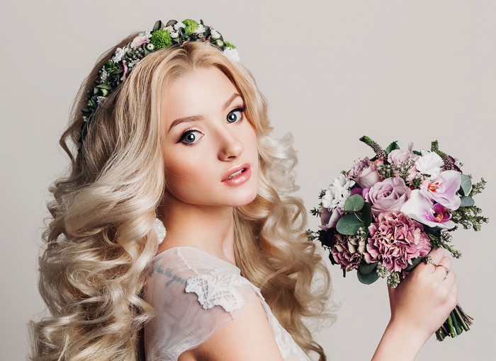 Blonde girl with curly hair and flower crown holding bouquet