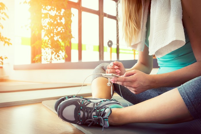 Woman with headphones and phone in gym