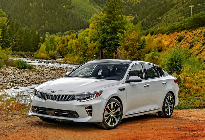 White Kia Optima parked by a river