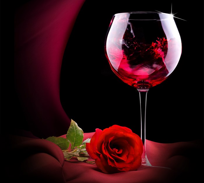 Red wine in a glass with a rose