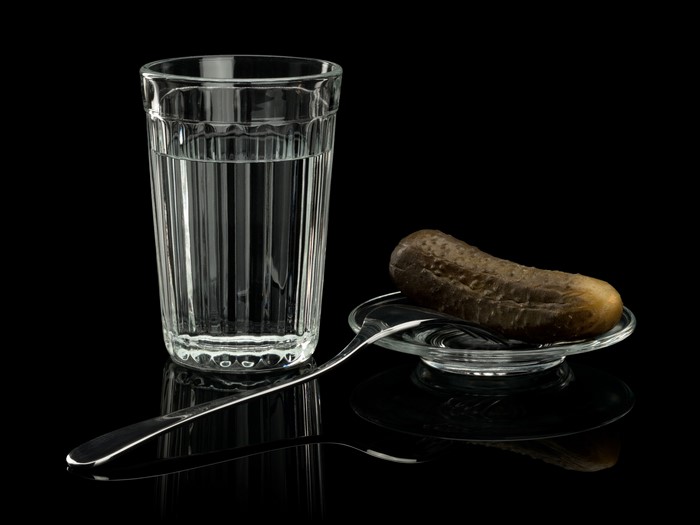 Glass of water and pickle with fork