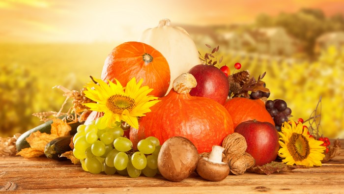 Autumn harvest arrangement with pumpkins, fruits, and sunflowers