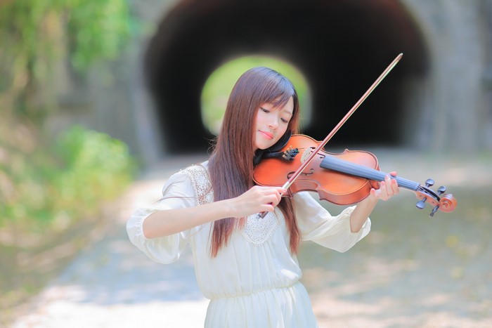 Asian woman playing violin in tunnel