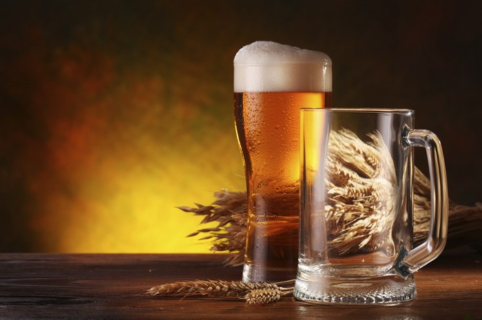 Beer in a glass and an empty mug with wheat