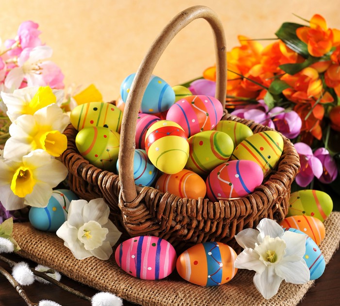 Easter eggs in a wicker basket with daffodils and tulips