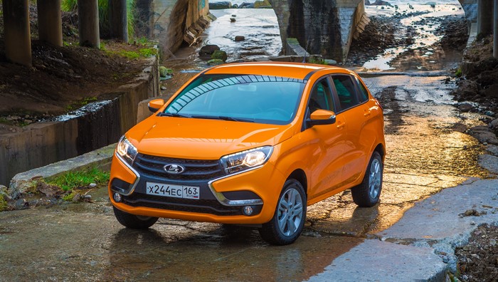 Orange Lada XRAY driving through a stream under a bridge