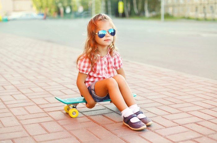 Little girl with sunglasses on a skateboard