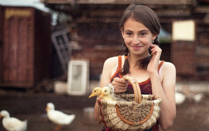 Girl holding a basket with ducklings