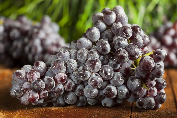 Grapes with water droplets on a wooden surface