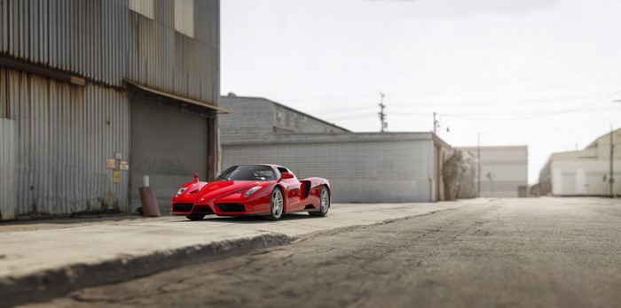 Red Ferrari Enzo parked near industrial buildings