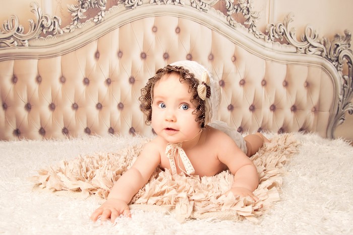 Baby in bonnet on a bed