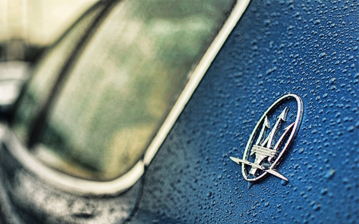 Maserati logo on a wet blue car