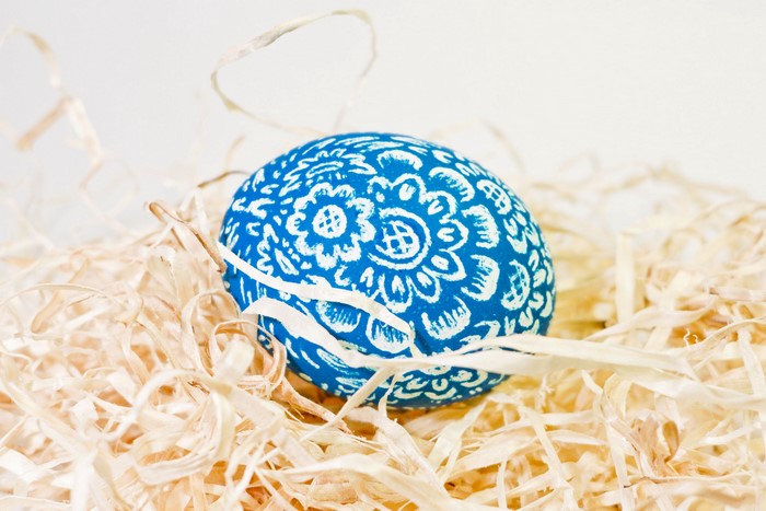 Blue Easter egg with white floral pattern in straw