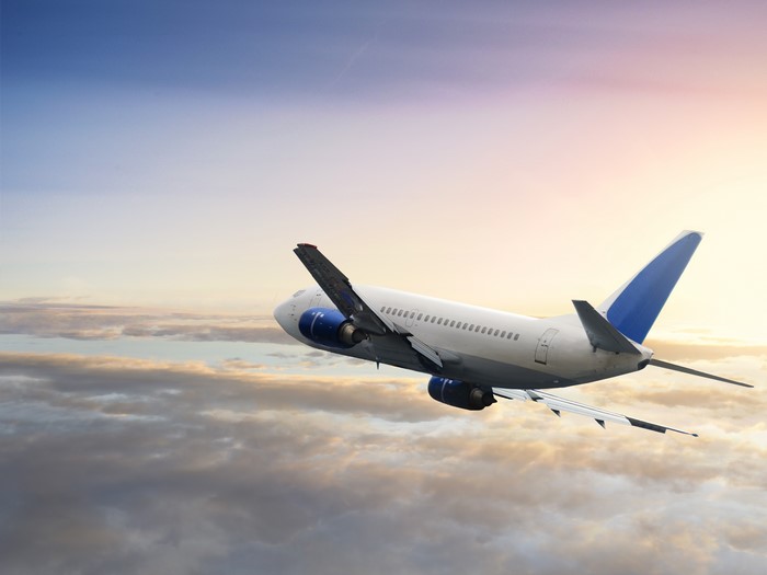 Airplane flying over clouds at sunset