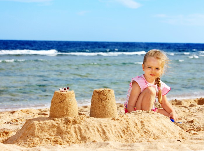 Little girl playing with sandcastles on the beach
