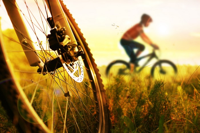 Close-up of a bicycle wheel with a cyclist in the background