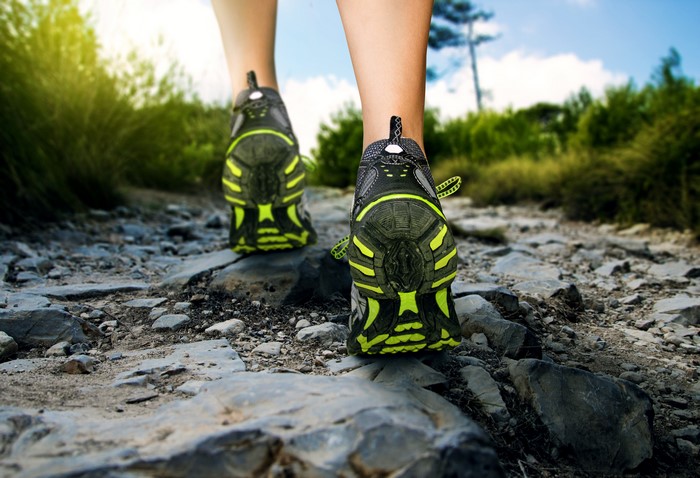 Legs wearing athletic shoes on a rocky path