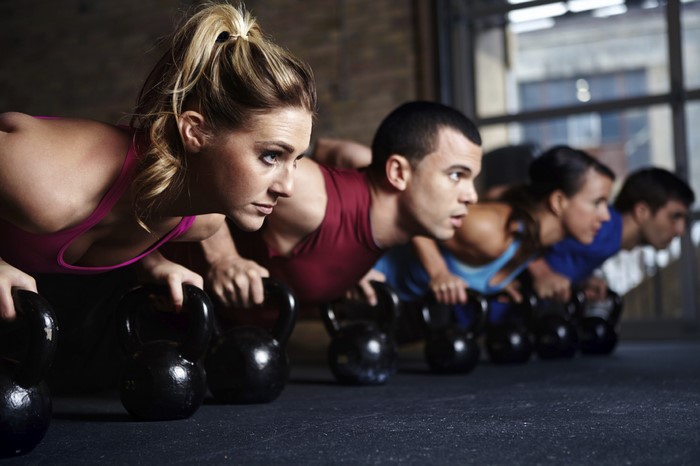 People doing kettlebell push-ups in a gym