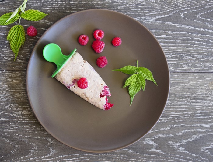 Raspberry ice pop with raspberries and leaves on plate
