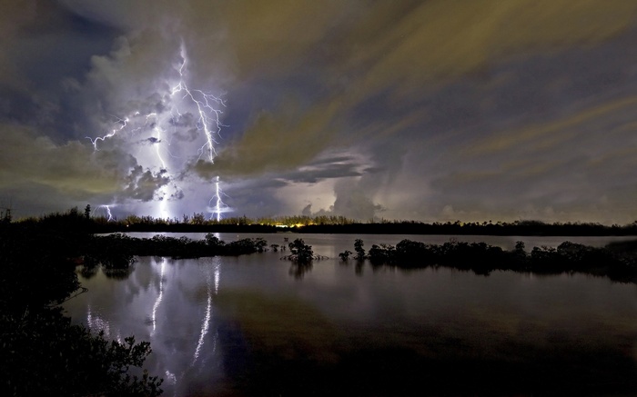 Lightning strikes over a body of water at night