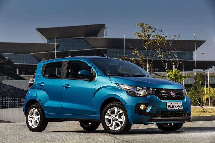 Blue Fiat Mobi Like parked in front of a modern building