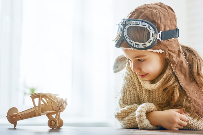 Girl in pilot hat with toy airplane