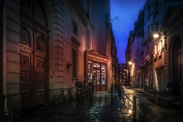Parisian street at night with a bookstore and streetlights