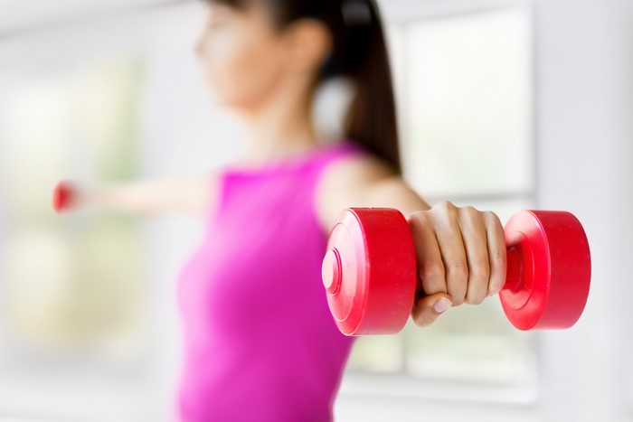 Woman exercising with red dumbbells