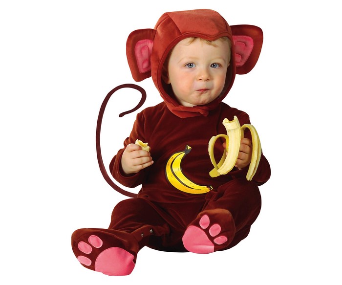 Baby in a monkey costume eating a banana