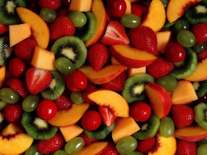 Assortment of fresh fruit including strawberries, kiwi, peaches, and grapes
