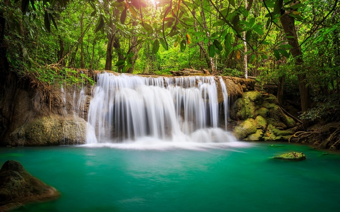Waterfall in a lush green forest with turquoise water