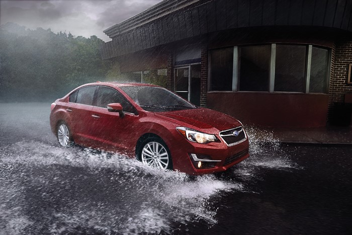 Red Subaru Impreza driving through rain