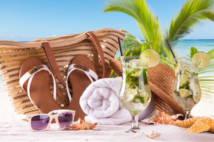 Beach scene with cocktails, bag, and flip-flops