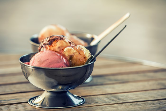 Ice cream sundaes in metal bowls on a wooden table