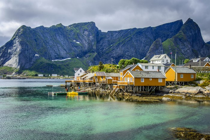 Yellow houses on stilts in Lofoten, Norway with mountains