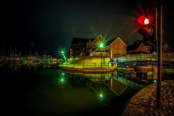 Night scene of a marina with houses and a traffic light