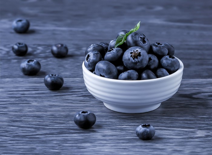 Blueberries in a white bowl on a wooden table