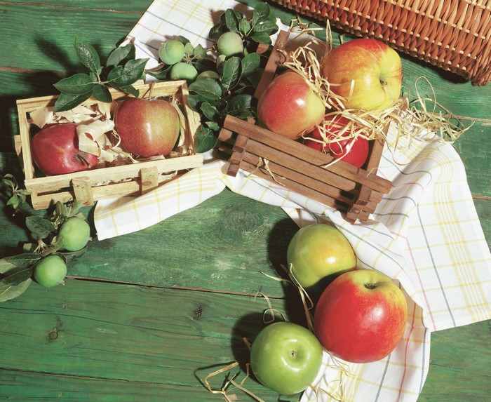 Apples in wooden crates on a green table