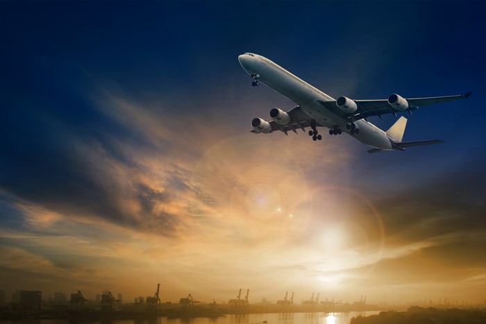 Airplane flying over a port at sunset