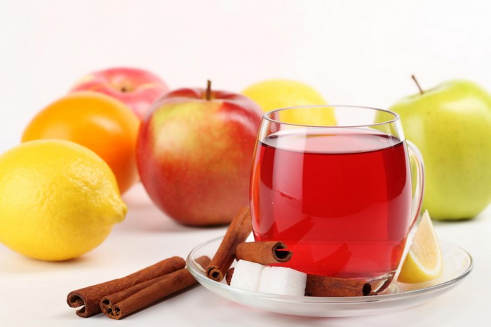 Glass of red juice with apples, lemons, and cinnamon