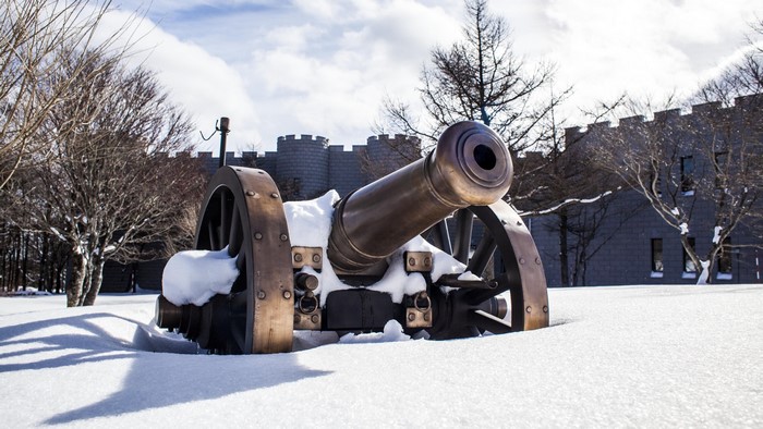 Cannon in the snow with castle in background