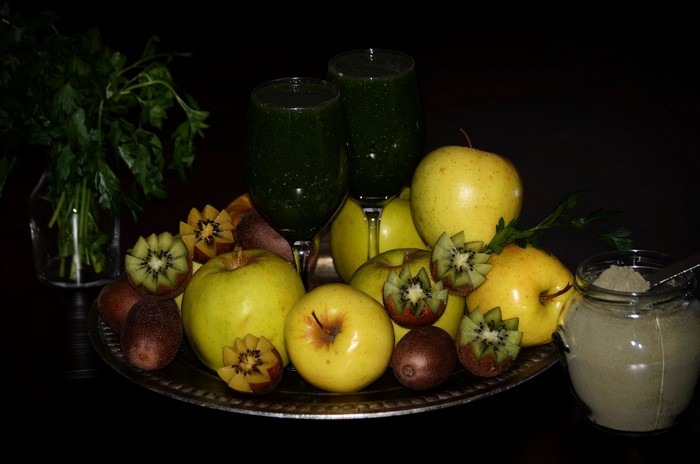 Apples, kiwi, juice, and parsley on a platter