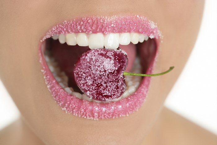 Woman with sugar-coated lips eating a cherry