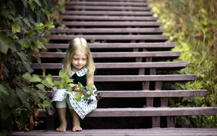 Little girl sitting on wooden stairs