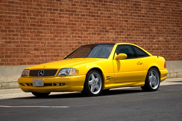 Yellow Mercedes-Benz SL 500 (R129) parked by brick wall
