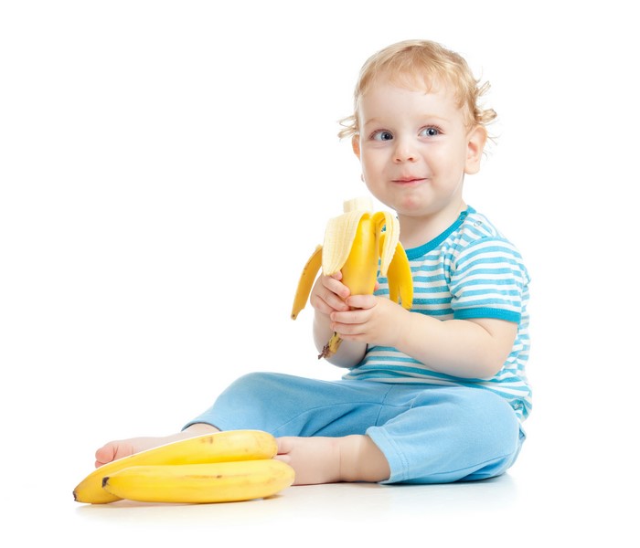 Boy eating a banana with other bananas