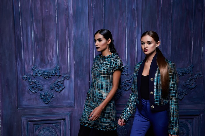 Two women in tweed outfits in front of a purple door