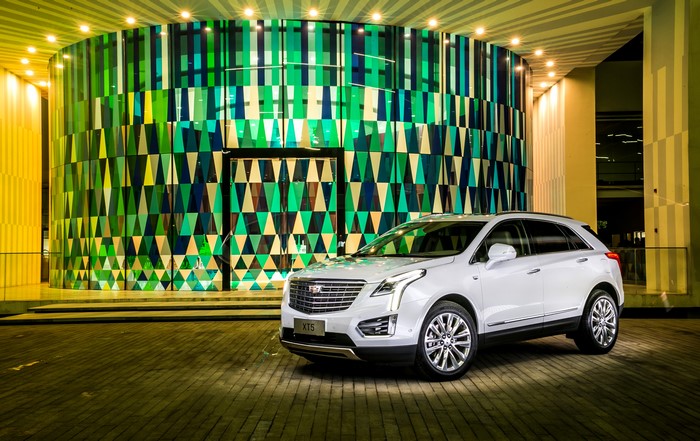 White Cadillac XT5 parked in front of a modern building