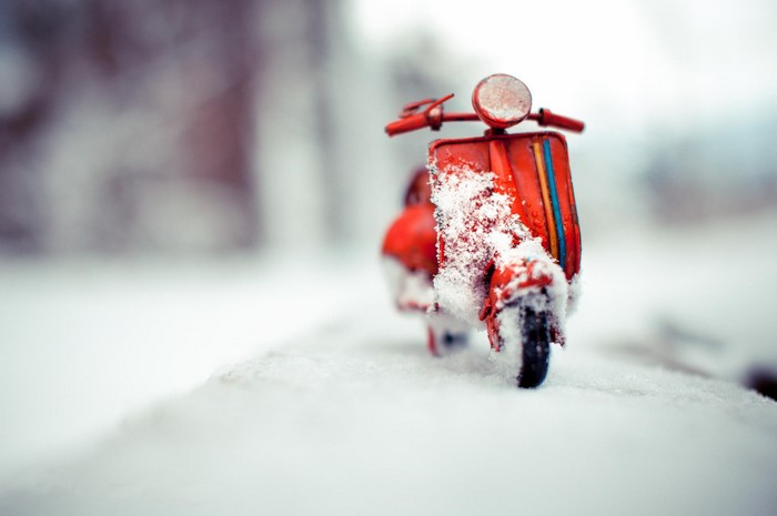 Red Vespa toy scooter covered in snow
