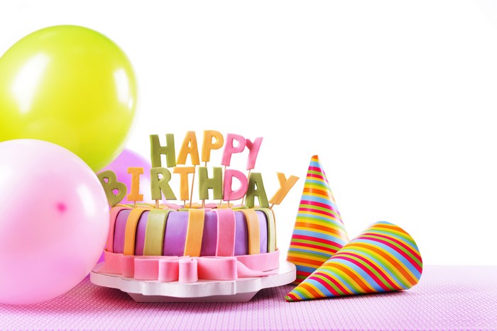 Birthday cake with balloons and party hats